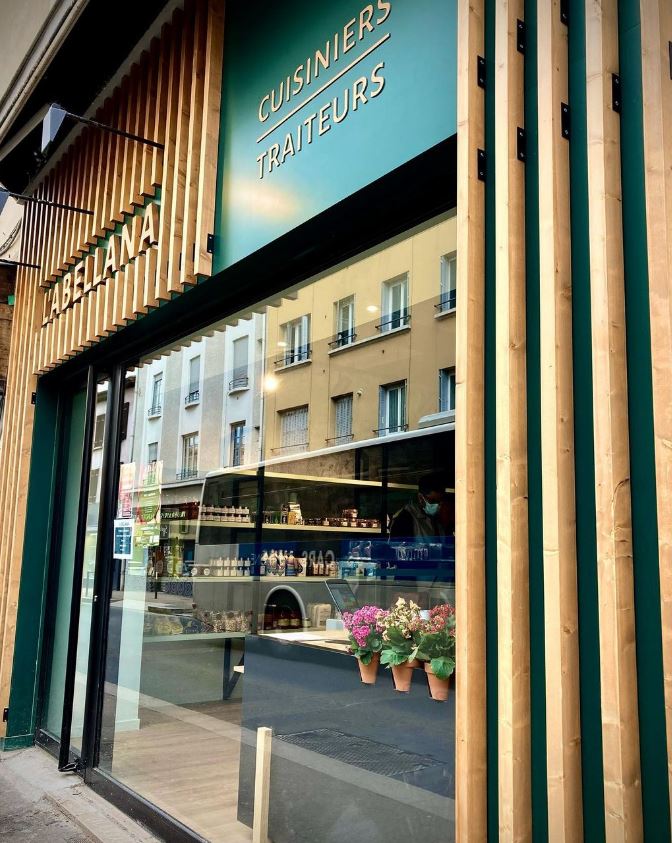 L'image montre la façade de la boutique du traiteur l'Abellana à Oullins. Elle montre des tasseaux bois, de la peinture verte et un logo en relief, en bois également