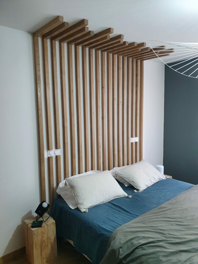 La photo montre une jolie tête de lit composée de tasseaux de bois brut